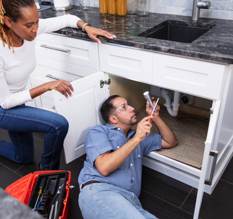 Handyman-looking-under-the-sink-in-the-kitchen Handyman looking under the sink in the kitchen